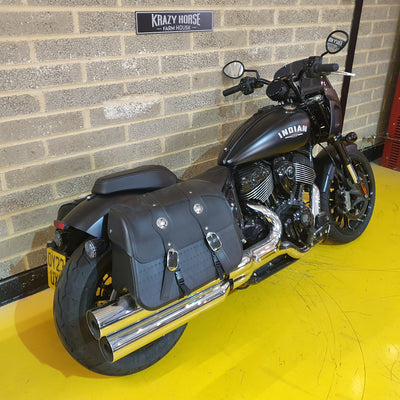 Black Indian motorcycle parked indoors against a brick wall.