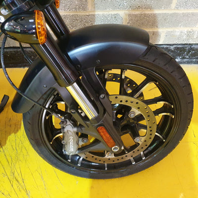 Close-up of a motorcycle wheel with disc brake on a yellow surface