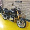 Norton motorcycle on a yellow floor with a brick wall background