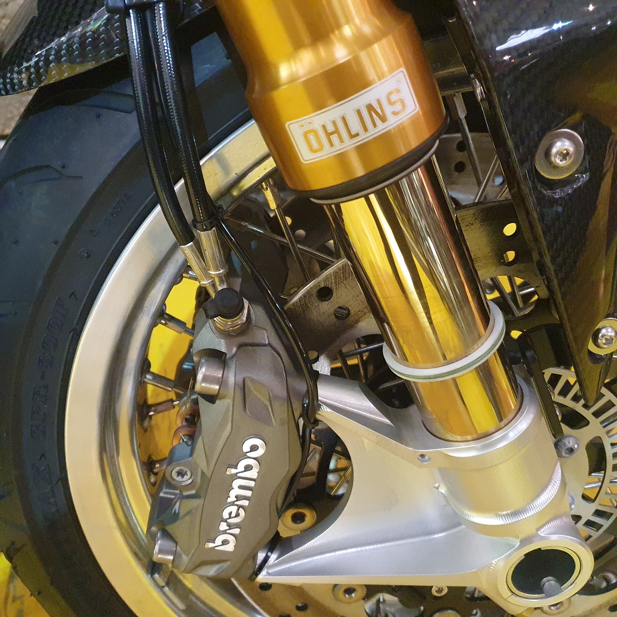 Close-up of a motorcycle suspension system with Ohlins and Brembo branding.