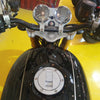 Close-up of a motorcycle's handlebar with dual gauges and brand logo on a yellow background.