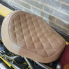 Beige quilted motorcycle seat against a brick wall background