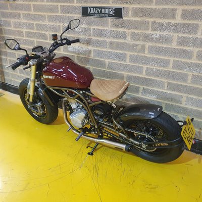 Motorcycle parked against a brick wall with a yellow floor.