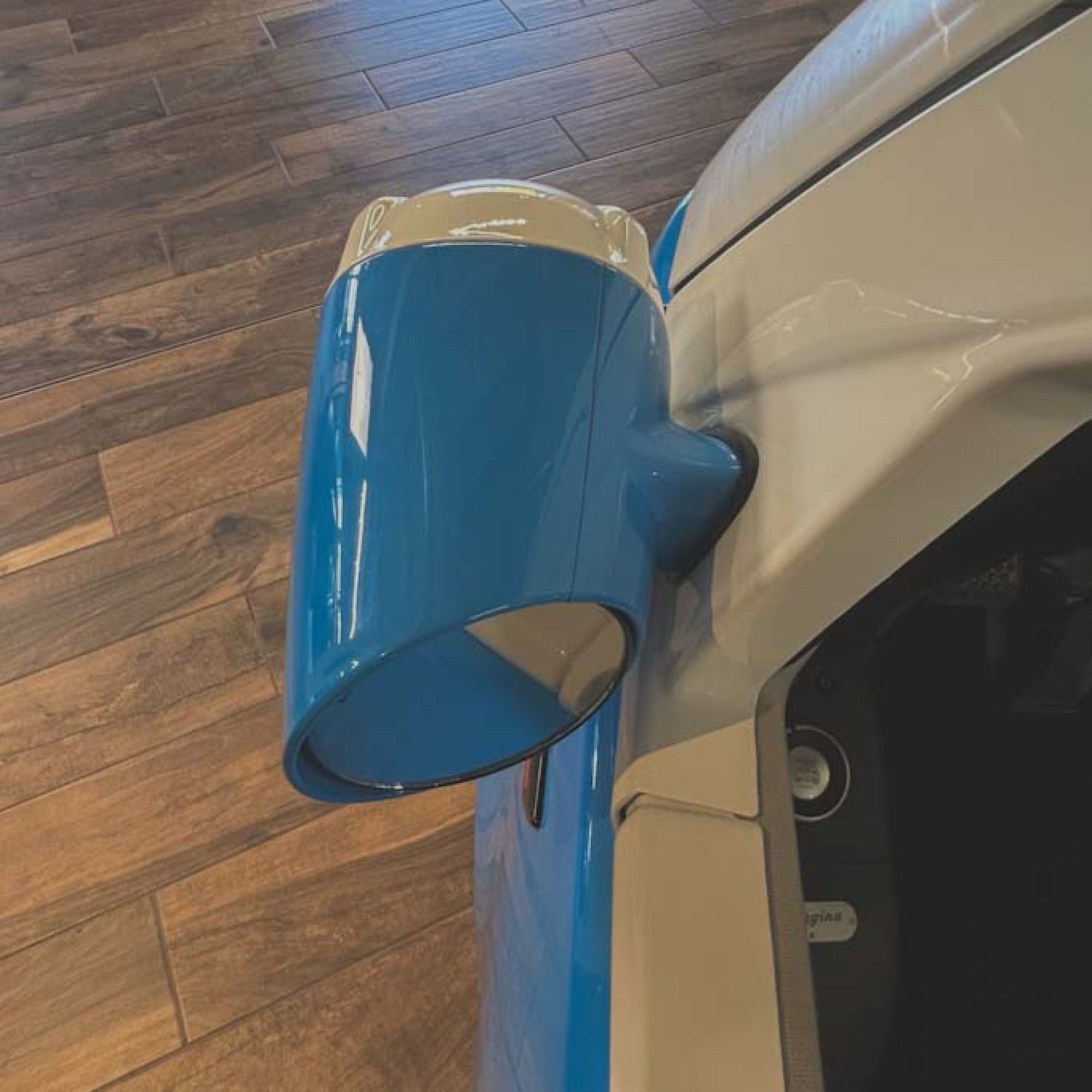 Blue car mirror on a vehicle with a wooden floor background