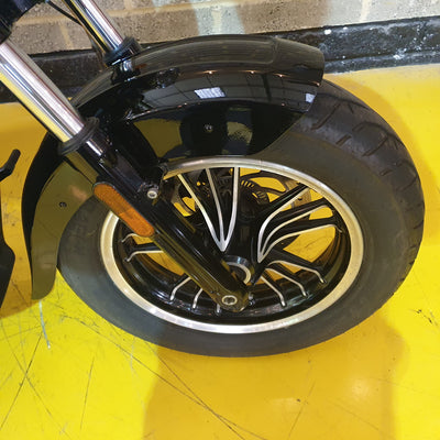 Close-up of a motorcycle wheel with a yellow background