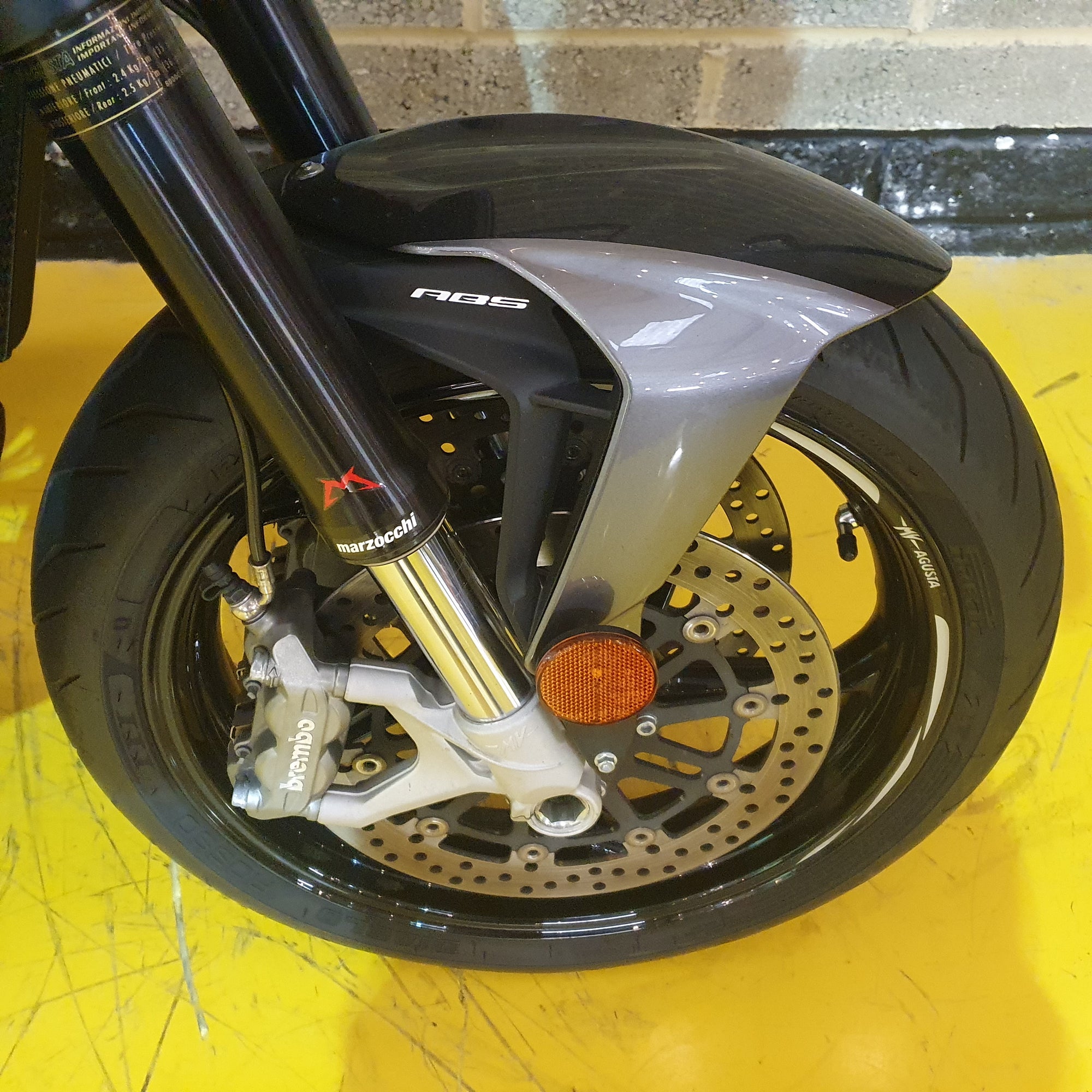 Close-up of a motorcycle wheel with suspension fork on a yellow surface