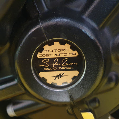 Close-up of a motorcycle engine cover with branding and text.