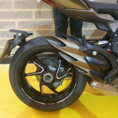 Close-up of a motorcycle wheel on a yellow surface with a brick wall background