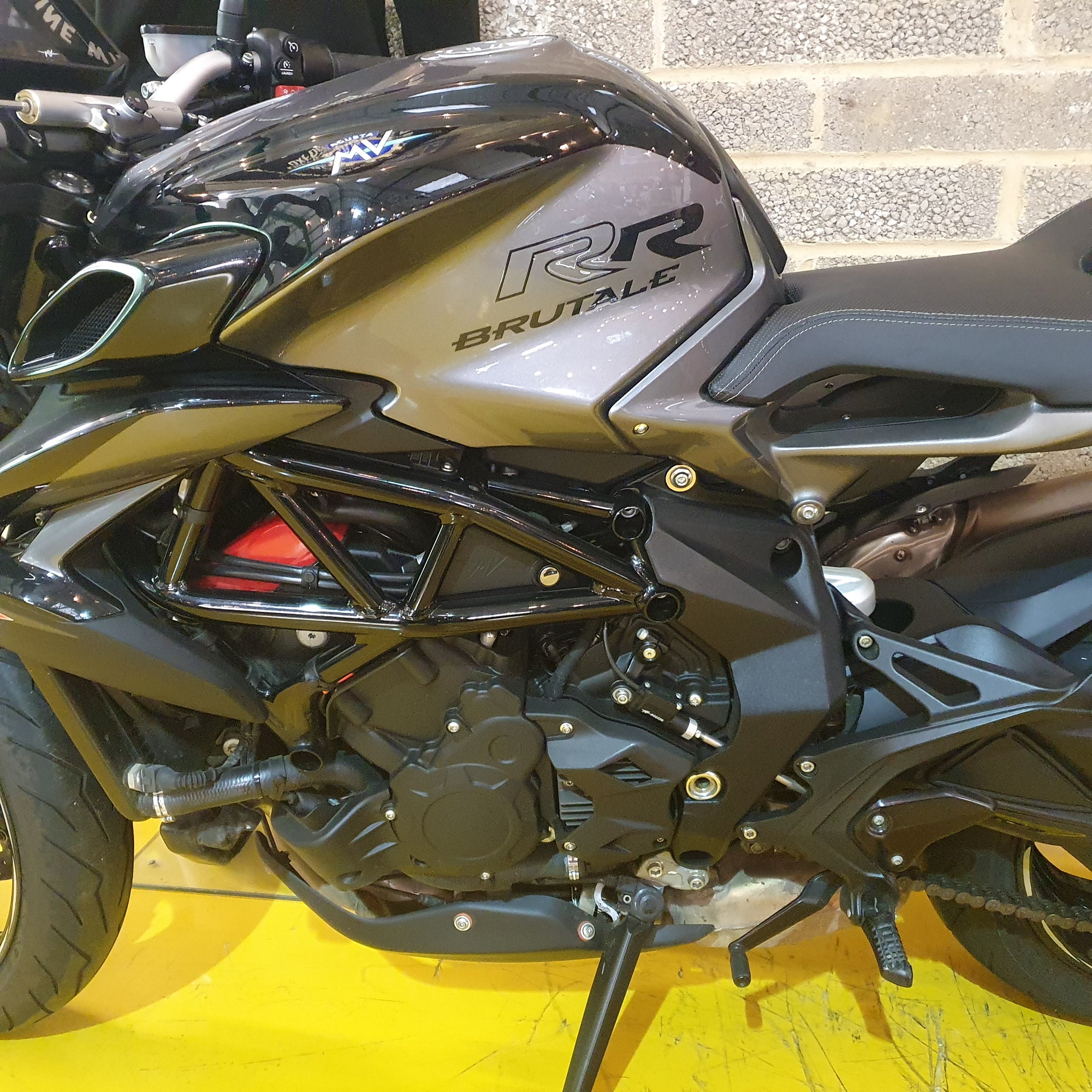 Close-up of a motorcycle with 'RR' branding on a yellow surface.