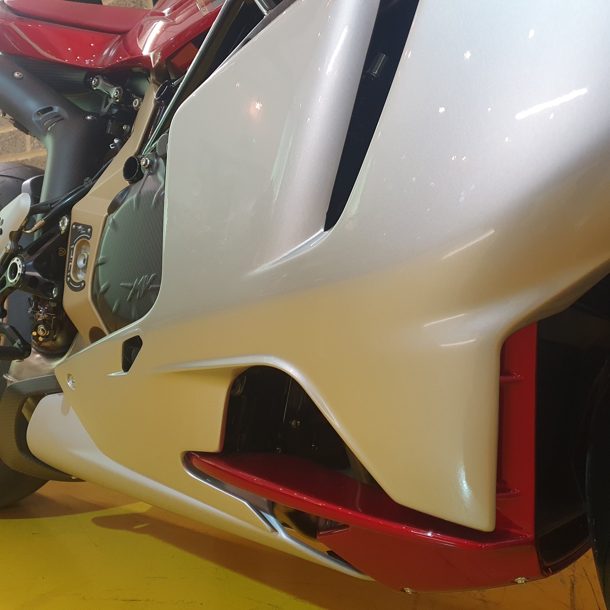 Close-up of a motorcycle's front fender and headlight on a yellow floor.