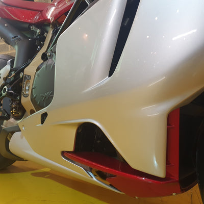 Close-up of a motorcycle's front fender and headlight on a yellow floor.