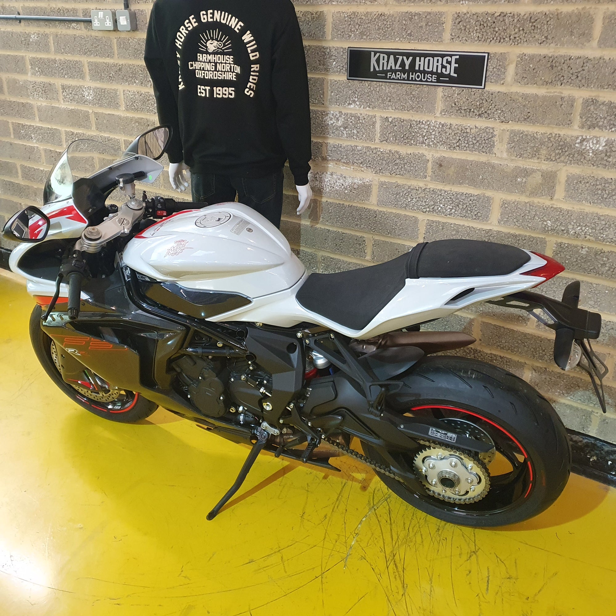 White and black motorcycle on a yellow floor with a brick wall background