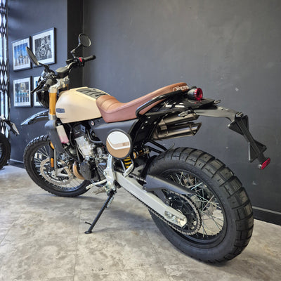 Motorcycle on display against a gray wall with framed pictures.