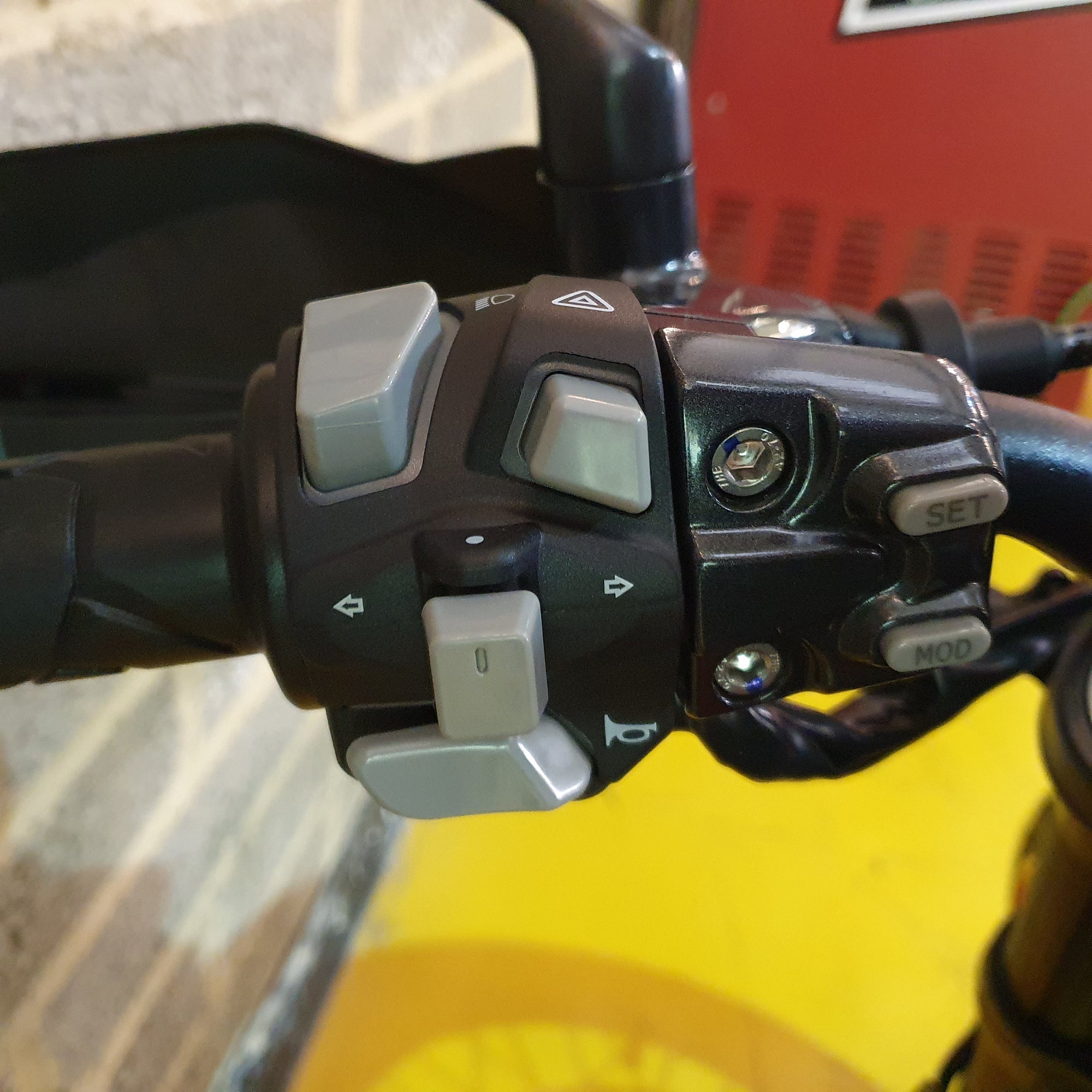 Close-up of motorcycle handlebar controls with buttons and switches.