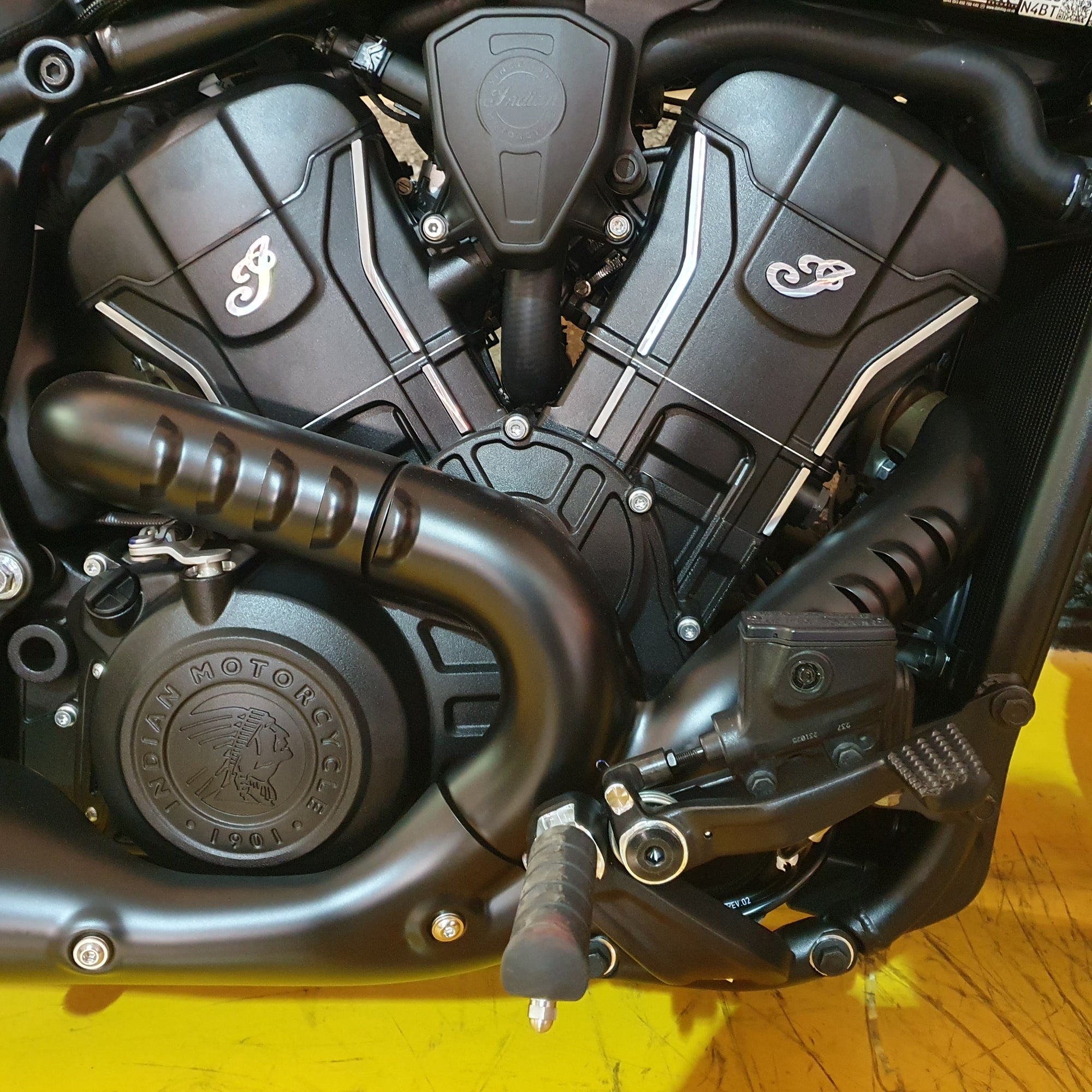 Close-up of a motorcycle engine with visible branding on a yellow background