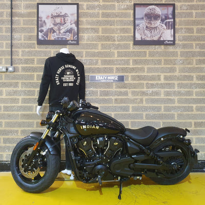 Black Indian motorcycle in a showroom with a brick wall and framed pictures.