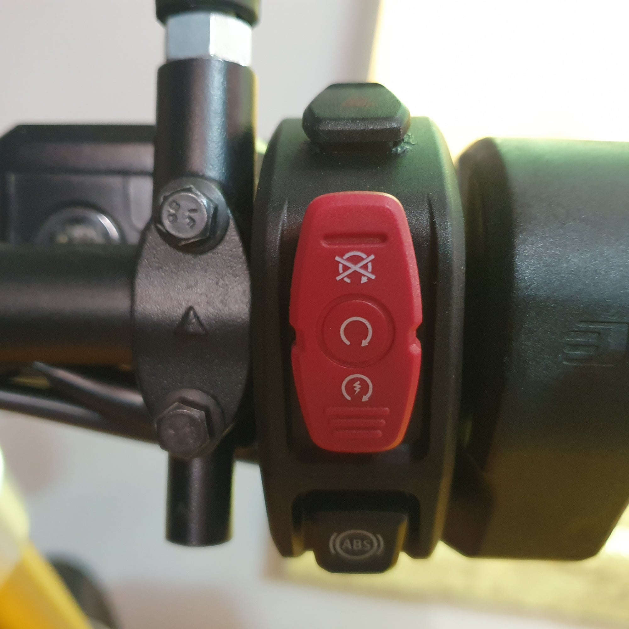 Close-up of a motorcycle handlebar with control buttons and ABS logo.
