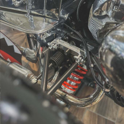 Close-up of a motorcycle suspension system with red spring and chrome components.