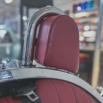 Close-up of a red leather seat with chrome metal in a blurred indoor setting