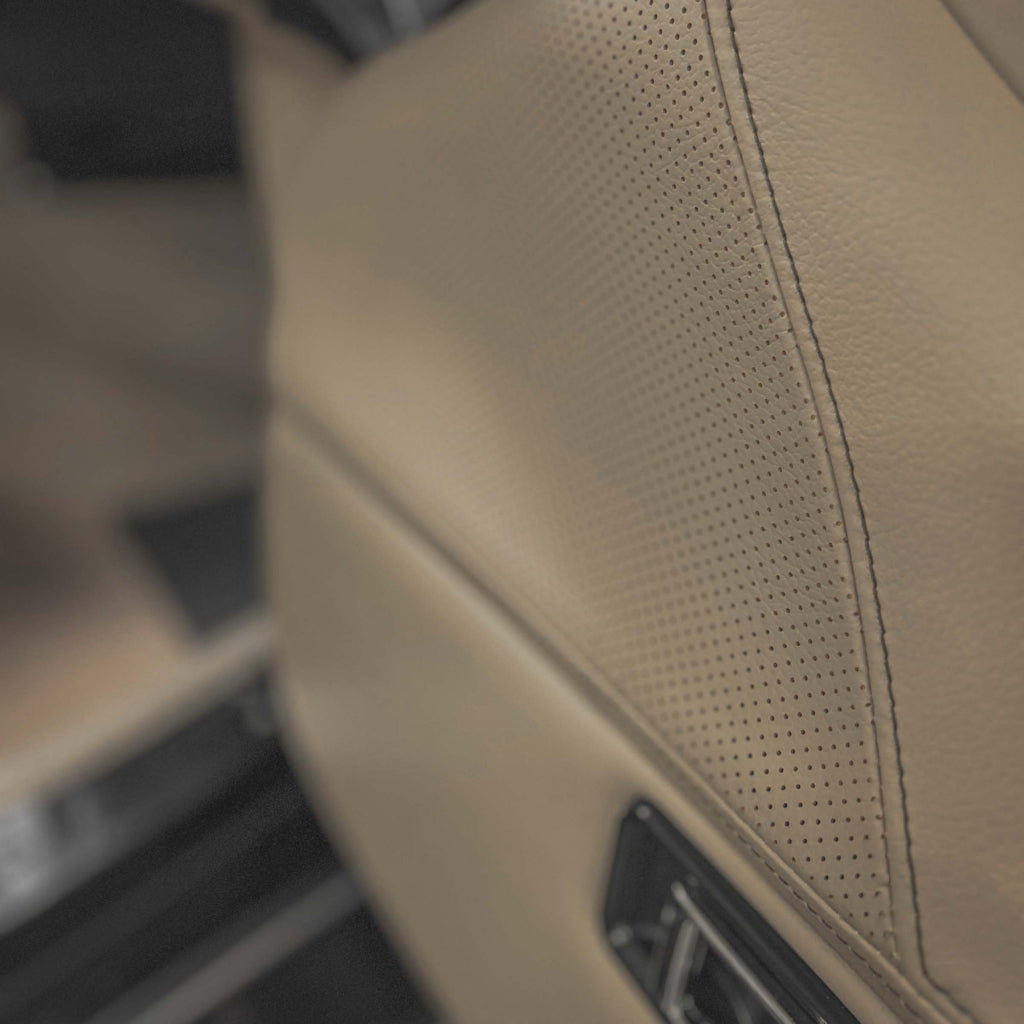 Close-up of a beige car interior panel with perforated texture.