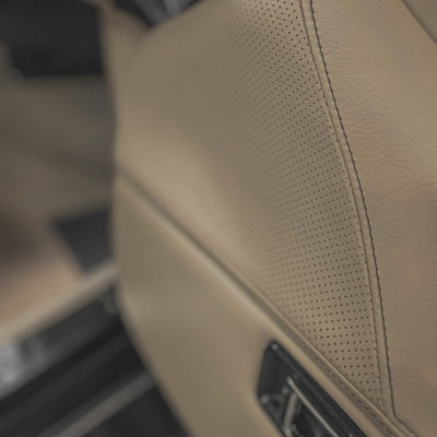 Close-up of a beige car interior panel with perforated texture.