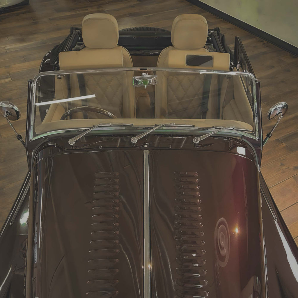 Vintage car interior with beige seats on a wooden floor.