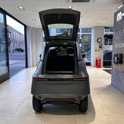Back view of a small electric vehicle in a showroom