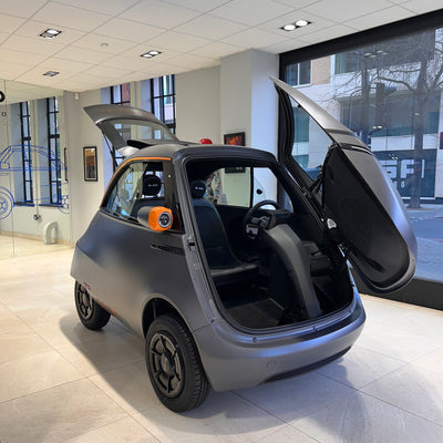 Small electric car with open doors in a showroom setting