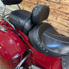 Close-up of a red motorcycle with black leather seats against a wooden background