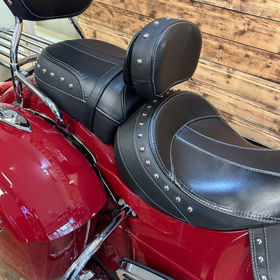 Close-up of a red motorcycle with black leather seats against a wooden background