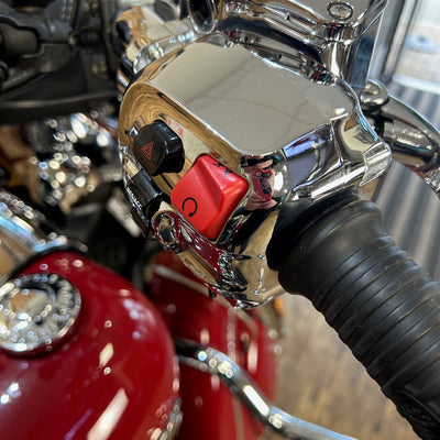 Close-up of a motorcycle handlebar with chrome and red elements.