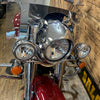 Close-up of a motorcycle's front headlight and chrome details with a wooden floor background.