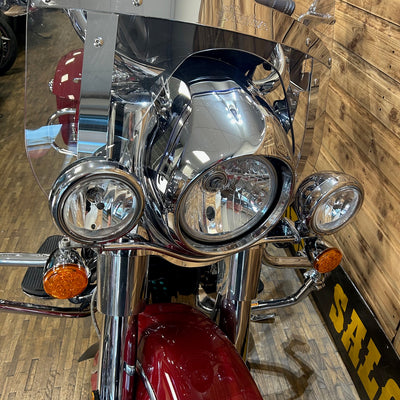 Close-up of a motorcycle's front headlight and chrome details with a wooden floor background.