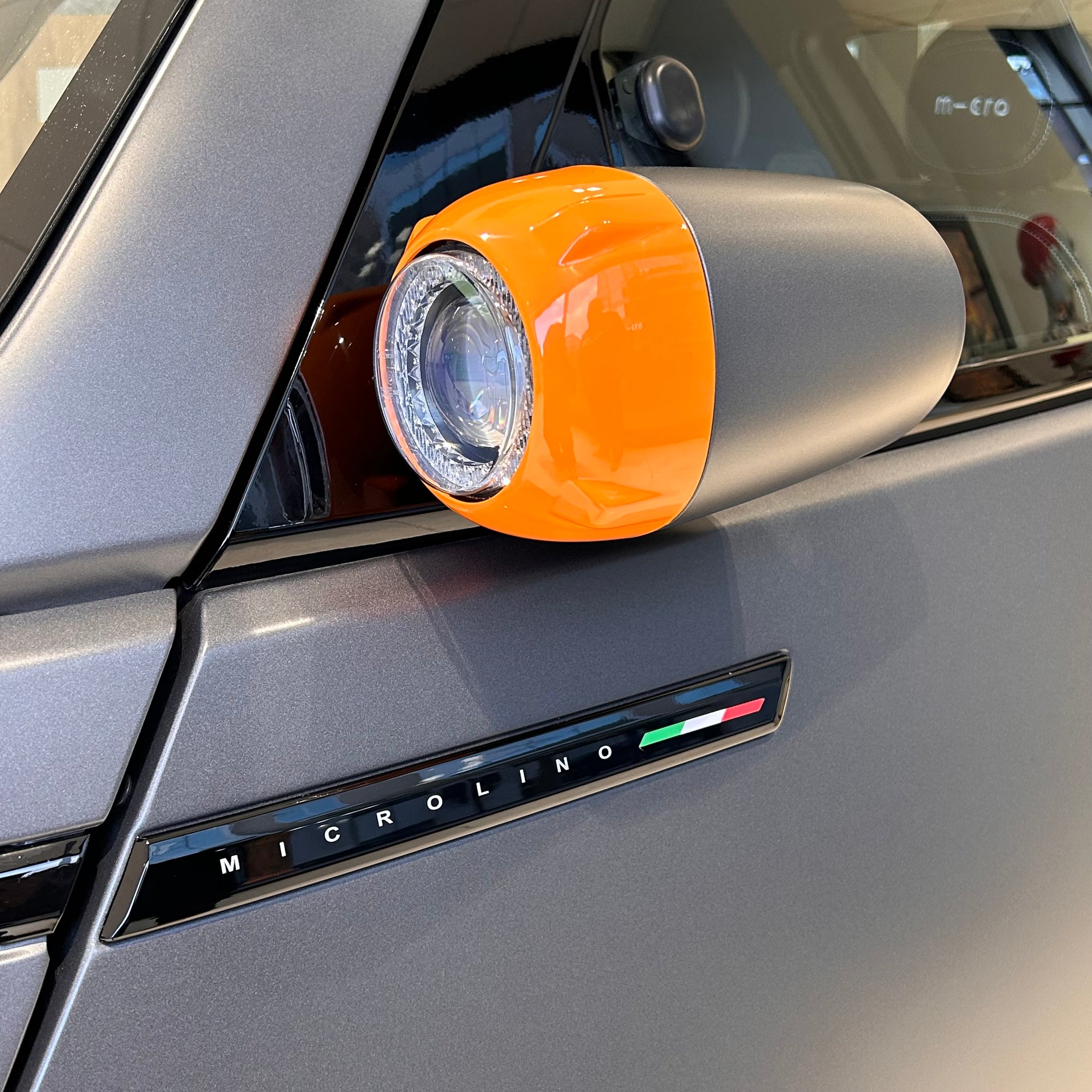 Close-up of a car's headlight with an orange cover on a Microlino vehicle.