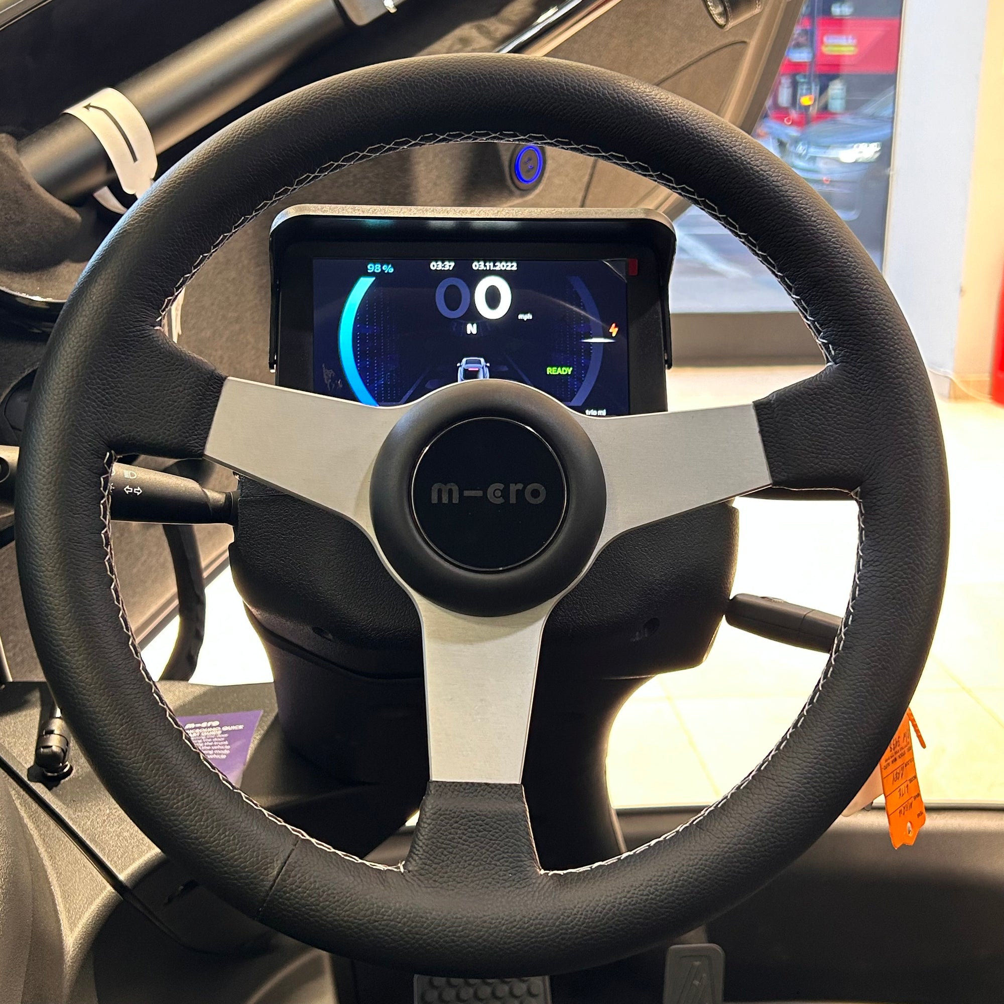 Steering wheel with a digital display and 'micro' branding inside a vehicle.