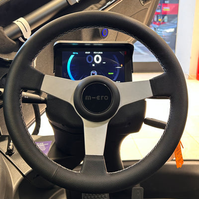 Steering wheel with a digital display and 'micro' branding inside a vehicle.