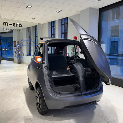 Small electric car with open door in a showroom setting