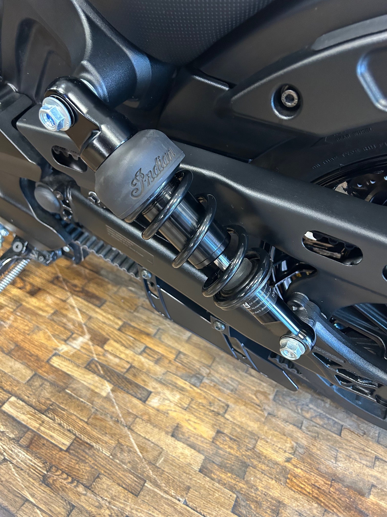 Close-up of a motorcycle suspension system on a wooden floor