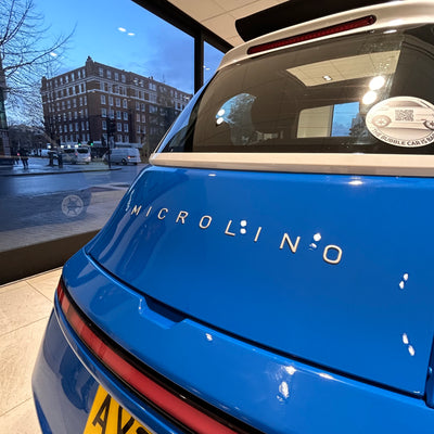 Blue Microlino car with a cityscape reflection in the window