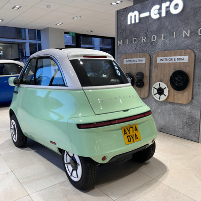 Small electric car in a showroom with 'Micro' branding.