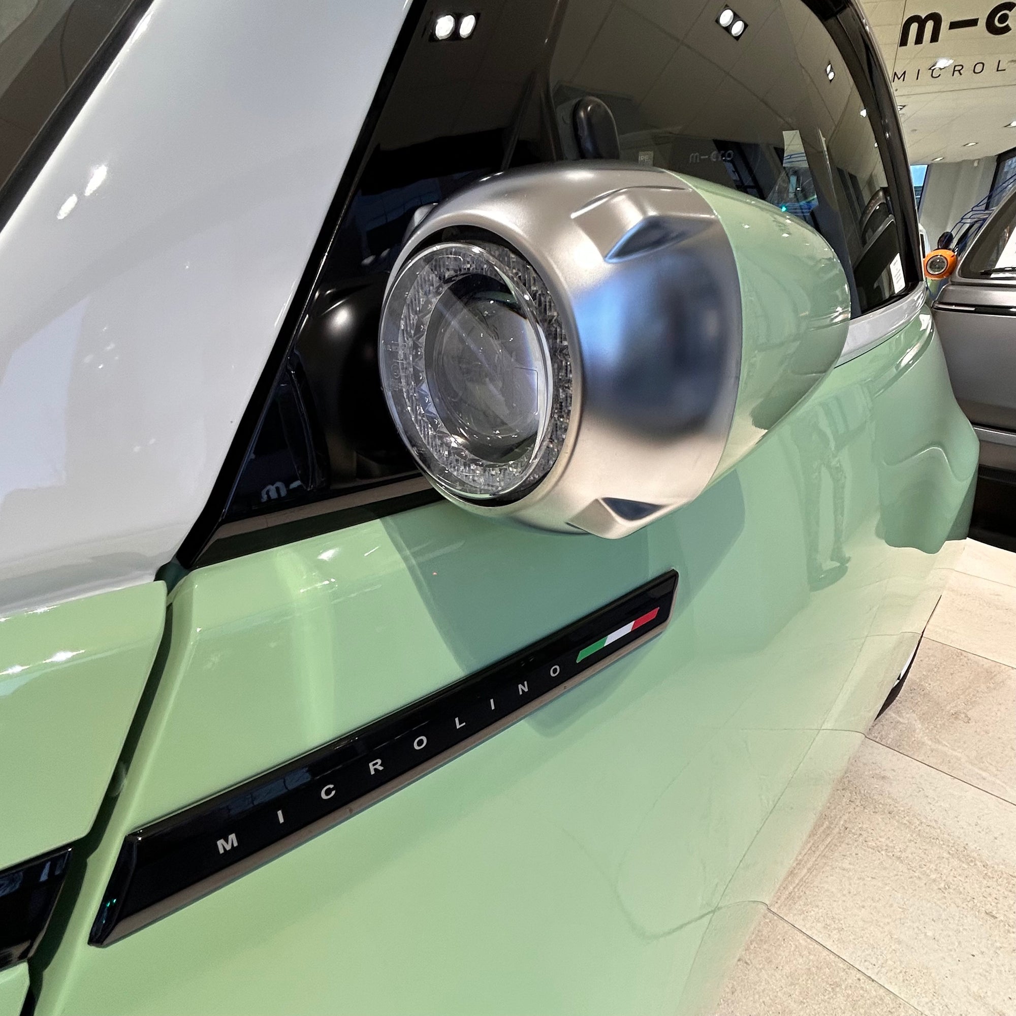 Close-up of a car's headlight and badge on a green vehicle with 'Microline' branding.