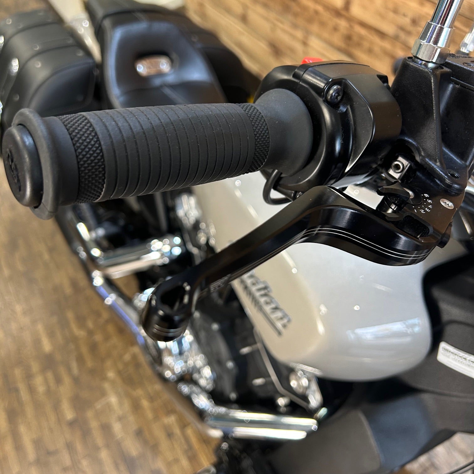 Close-up of motorcycle handlebar with throttle and brake lever on a wooden floor background