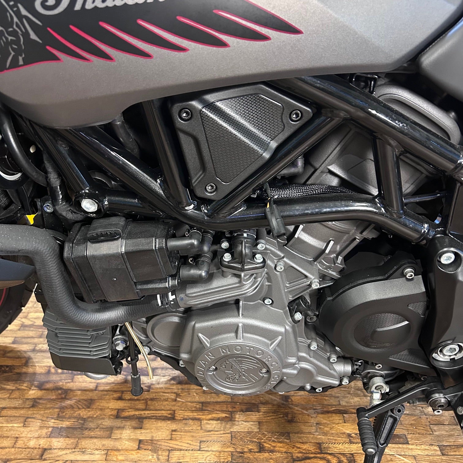 Close-up of a motorcycle engine with visible branding on a wooden floor.