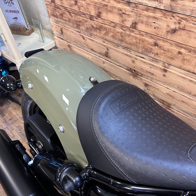 Close-up of a motorcycle seat with a brand logo against a wooden wall.