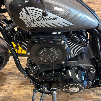 Close-up of an Indian motorcycle engine with 'Indian' branding on a wooden floor.