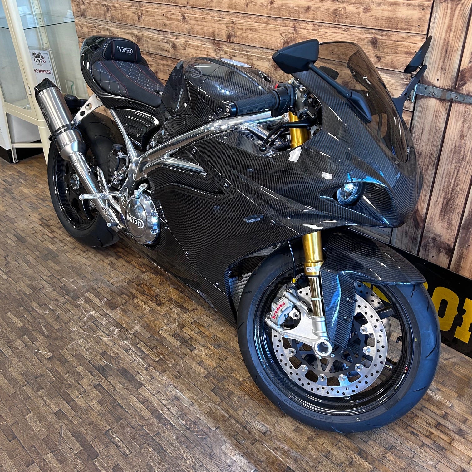 Black sports motorcycle on a wooden floor with a wooden wall background