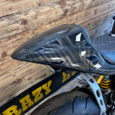 Carbon fiber motorcycle seat against a wooden background