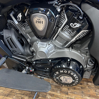 Close-up of a motorcycle engine with 'Indian Motorcycle' branding on a wooden floor.