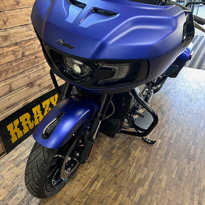 Blue motorcycle on a wooden floor with a sign in the background