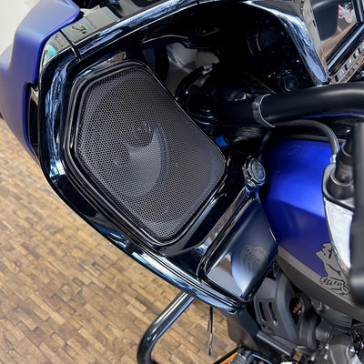 Close-up of a motorcycle's headlight and grille on a tiled floor.